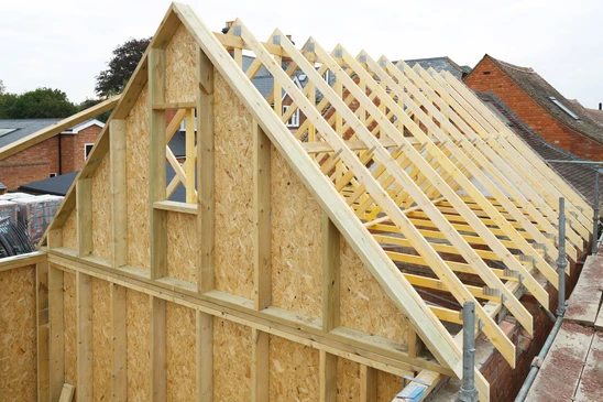 Chantier de construction résidentielle en extérieur avec charpente bois en cours d'édification