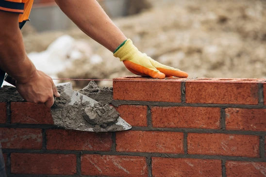 Chantier de construction en extérieur avec coulage de béton frais depuis une benne de camion toupie vers des coffrages en bois