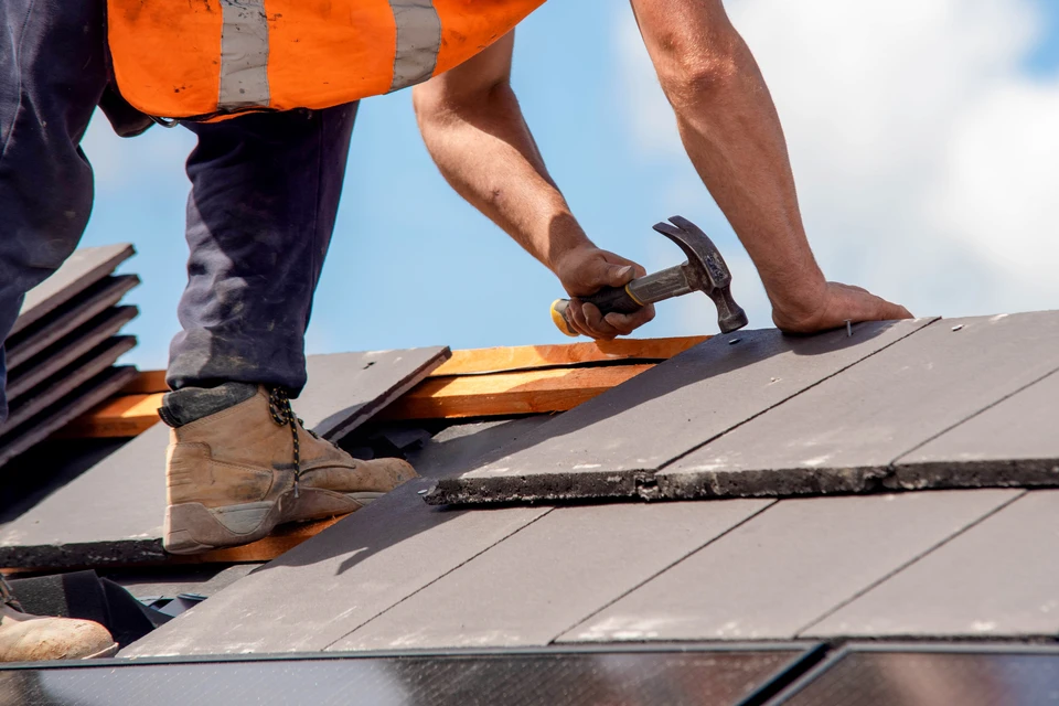 Ouvriers en équipement de protection sur toiture métallique, utilisant perceuse électrique pour installation