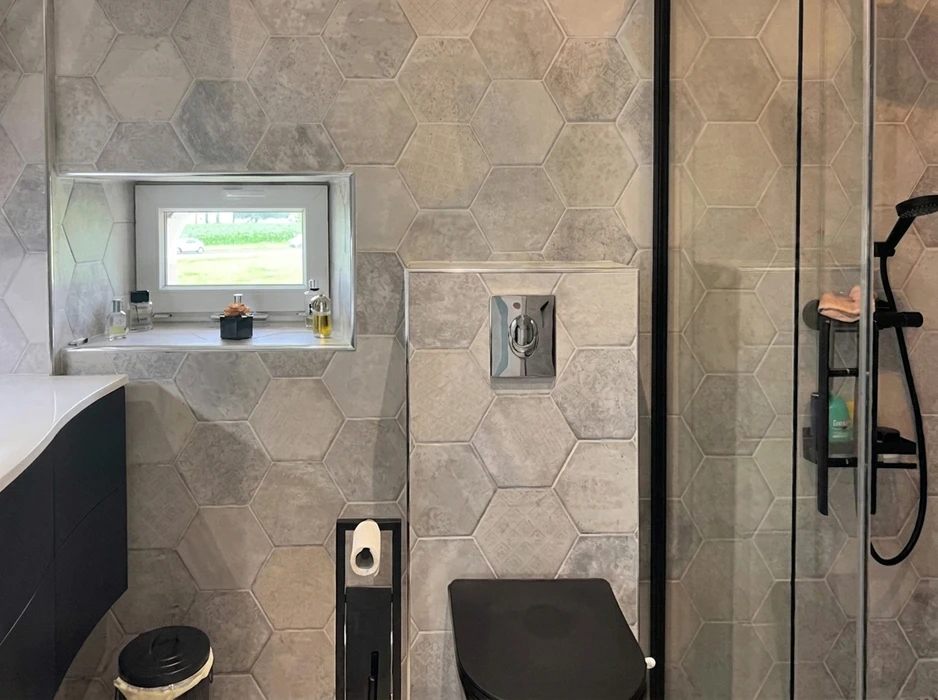 Artisan carreleur à genoux installant un revêtement de sol en carreaux de grès beige selon un motif géométrique