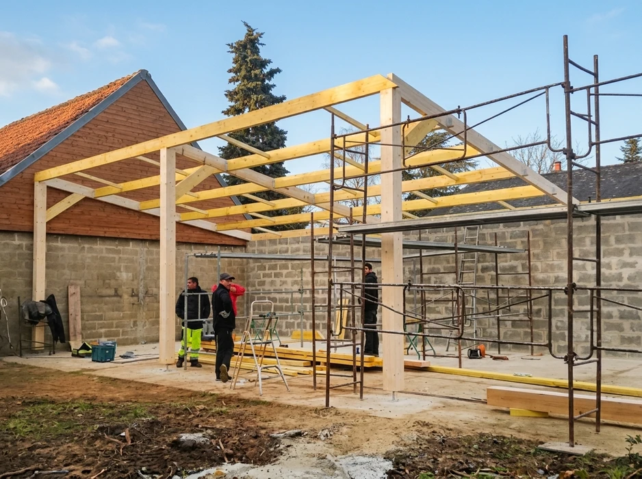 Chantier de construction résidentielle en cours, structure bois avec isolation thermique rose entre montants et solives apparentes